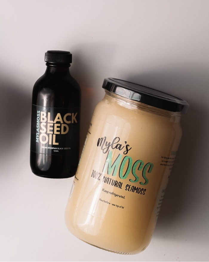Bottle of Mylasmoss black seed oil beside a jar of Myla's Moss sea moss gel